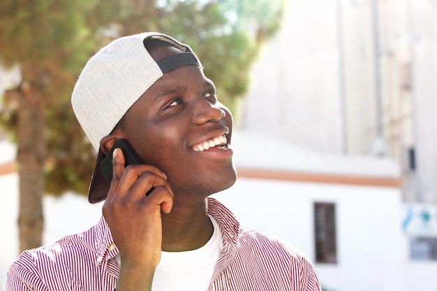 Cerrar alegre joven hablando por teléfono celular afuera