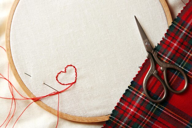 Cerrar el aro de bordado con lienzo e hilos de coser rojos en la mesa