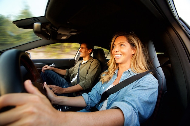 Cerrar atractiva pareja riendo en coche en viaje por carretera