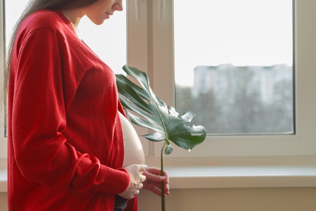 Cerrar barriga de mujer embarazada con exóticas hojas verdes