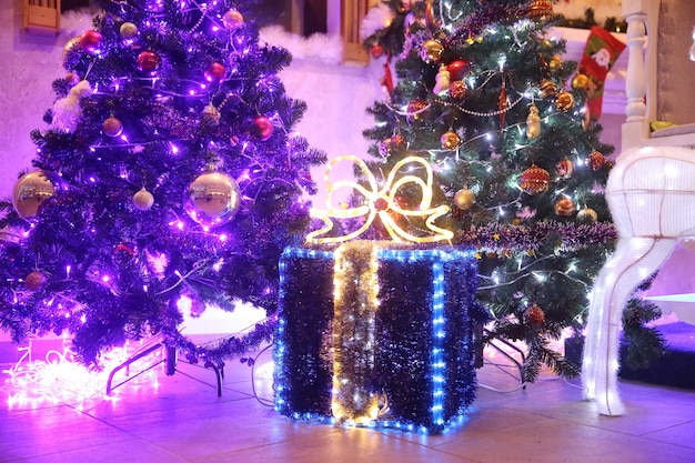 Cerrar caja grande con regalos de Navidad cerca del árbol de Navidad en la sala de estar