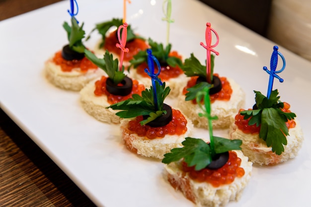 Foto cerrar en canapé con plato de caviar rojo