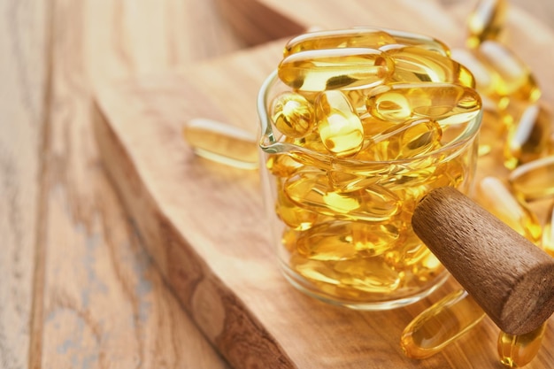 Cerrar cápsulas con vitamina DE o ácidos grasos Omega 369 en botella sobre fondos de madera viejos Suplemento alimenticio aceite de pescado lleno de aceite Suplementos naturales para un concepto de buena vida saludable Banner
