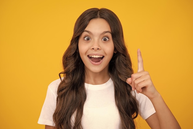 Cerrar la cara graciosa del joven adolescente apuntando hacia arriba con el dedo aislado sobre fondo amarillo Chica tiene una gran idea nueva Niño exitoso