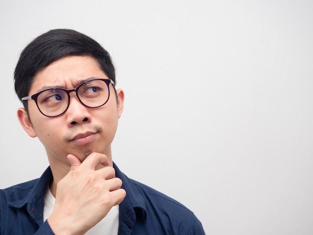 Cerrar la cara del hombre asiático con gafas pensando y mirando el fondo blanco del espacio de la copia