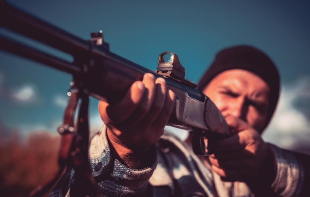 Cerrar carabina de francotiradores en el cazador de armas de caza de caza al aire libre apuntando con rifle en ingenio de cazador forestal