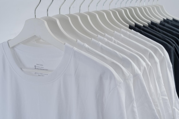 Cerrar colección de camiseta de color blanco y negro colgada en percha de madera