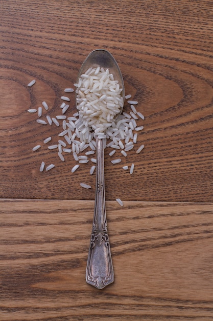 Cerrar una cucharadita de arroz en la mesa de madera. Montón de arroz crudo crudo blanco.