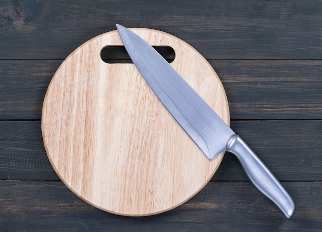 Foto cerrar un cuchillo de cocina y una tabla de cortar redonda sobre una mesa de madera