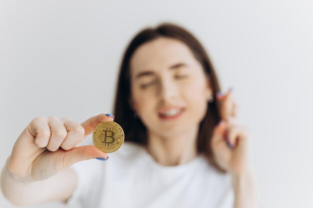 Cerrar diversión emocional mujer joven está sosteniendo bitcoin frente al ojo Concepto de moneda virtual en línea