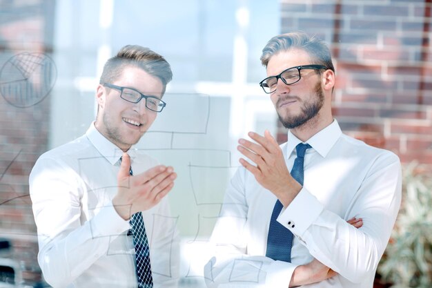 Foto cerrar dos empleados hablando de pie en la oficina los días laborables