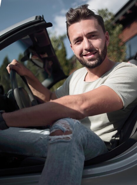 Cerrar elegante joven sentado en convertible ca