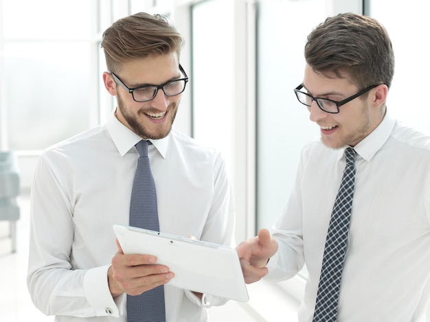 Cerrar empleados alegres mirando la pantalla de la tableta digitalpersonas y tecnología