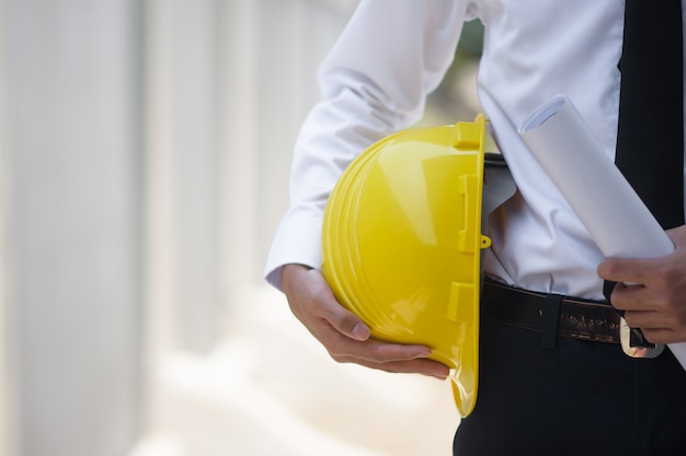 Cerrar empresario sosteniendo amarillo constructor de casco duro finca de construcción