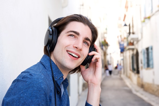 Cerrar feliz joven con auriculares en calle de la ciudad