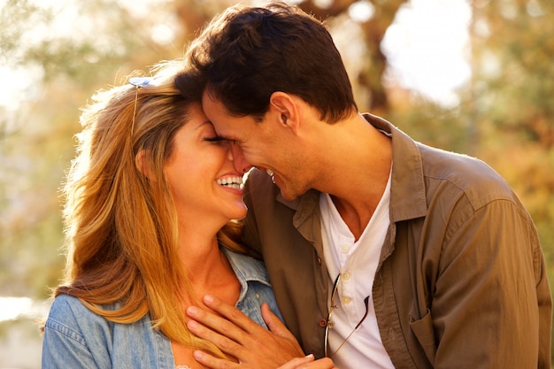 Cerrar feliz pareja de pie juntos riendo en estrecho abrazo