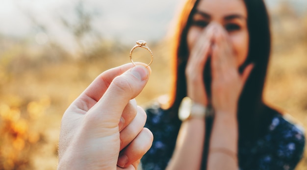 Cerrar la foto de un anillo de bodas con un diamante que se muestra a la niña mientras ella está asombrada y cubre su rostro con las palmas