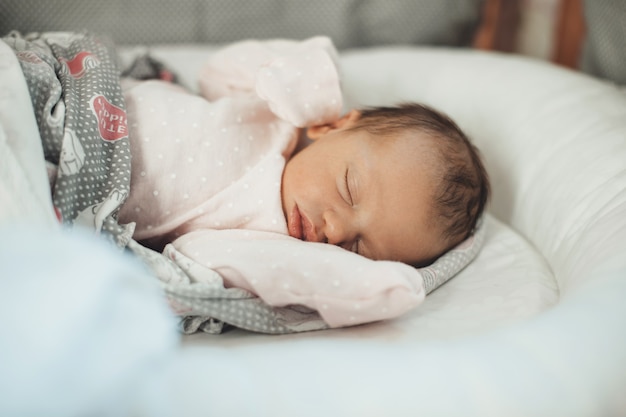 Cerrar foto de un bebé recién nacido durmiendo en ropa de abrigo cubierto con una colcha en su cama