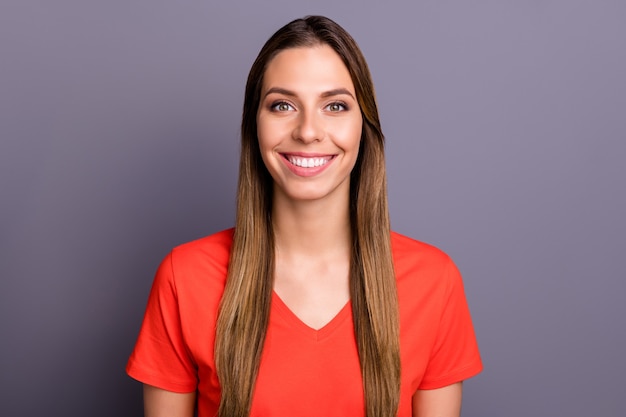 Cerrar una foto de una bonita dama morena en camiseta roja posando contra la pared púrpura