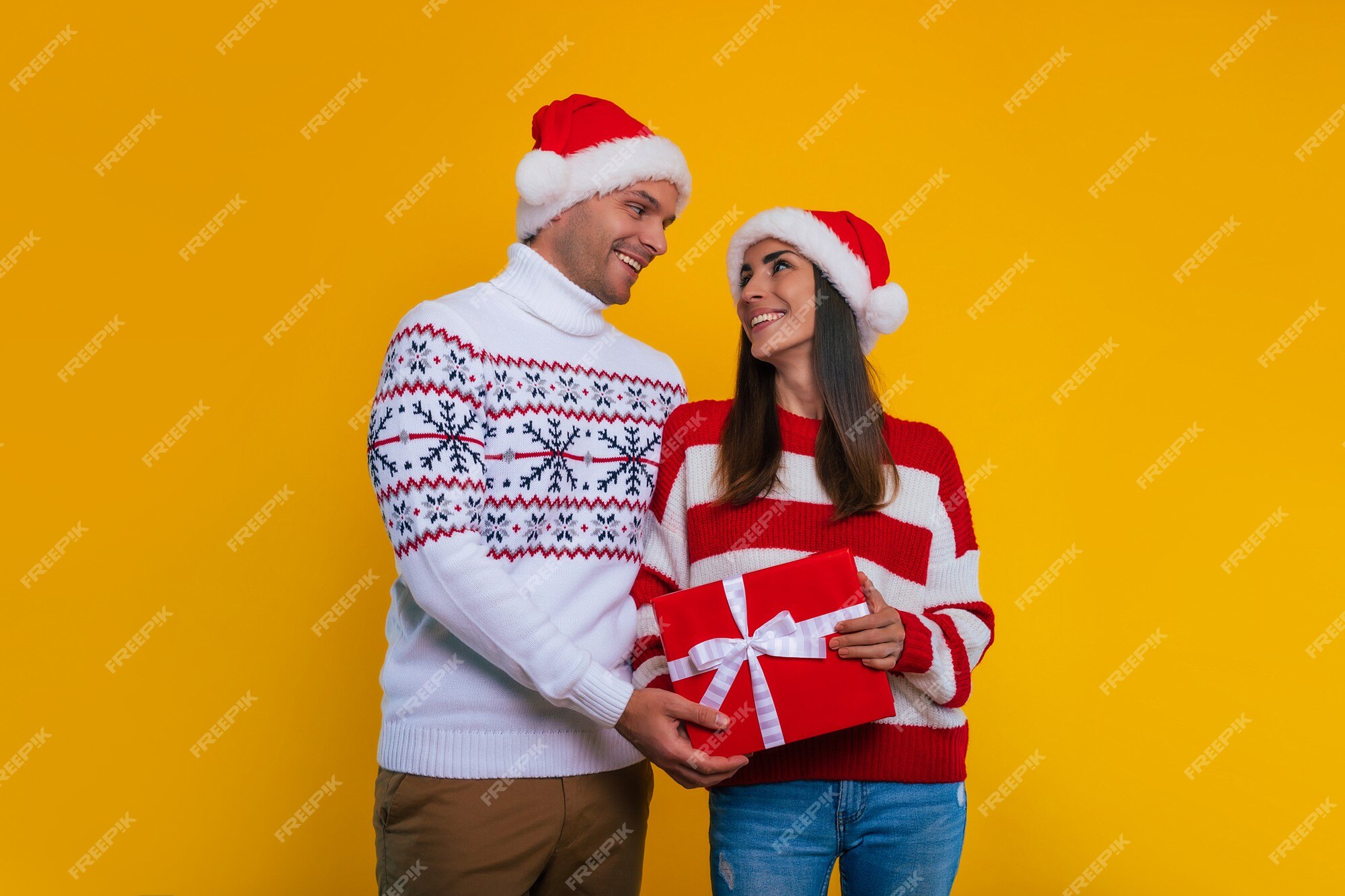 Cerrar una foto de la hermosa joven pareja feliz y emocionada enamorada en  ropa de navidad con cajas de regalo en las manos mientras celebran el año  nuevo y dan regalos el