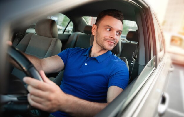 Foto cerrar foto de joven apuesto hombre de éxito está conduciendo su coche moderno