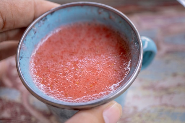 Cerrar foto de jugo de fresa fresco en la taza azul en la tienda de jardinería