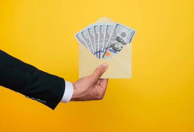 Cerrar foto de manos masculinas jóvenes sosteniendo los muchos dólares de EE. UU. Aislado sobre fondo amarillo
