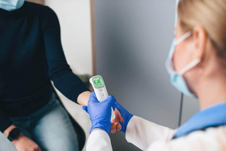 Foto cerrar foto de un médico senior caucásico usando un termómetro electrónico para medir la temperatura del paciente