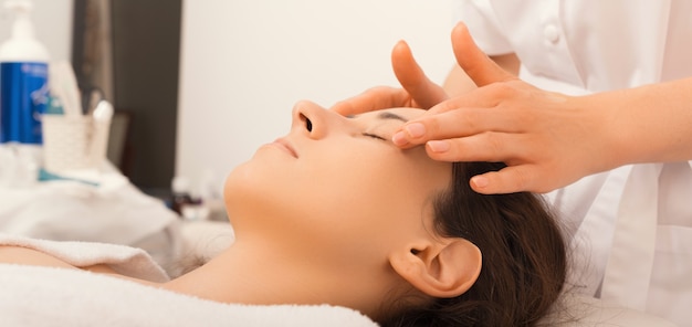 Cerrar foto de mujer haciendo tratamiento facial de la piel y masajeando a la cosmetóloga