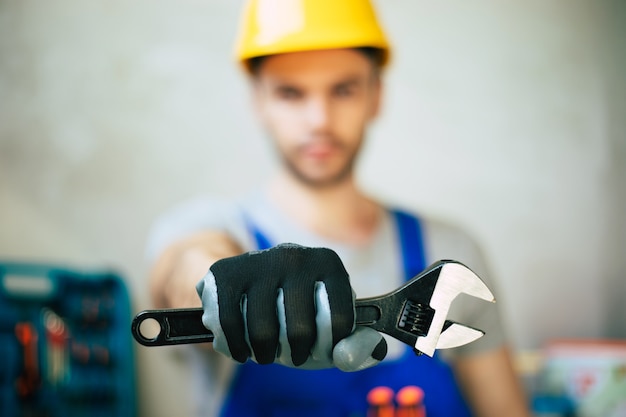 Cerrar foto de reparador profesional en uniforme y casco de seguridad tiene en manos nuevas herramientas modernas para trabajo y renovación