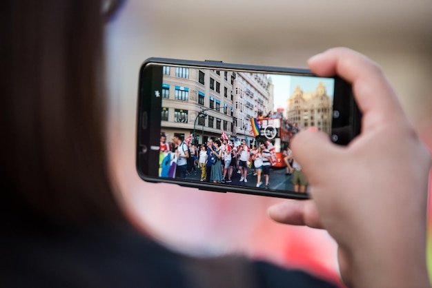 Cerrar fotografía mujer tomando fotos con su teléfono inteligente durante el desfile del día del orgullo