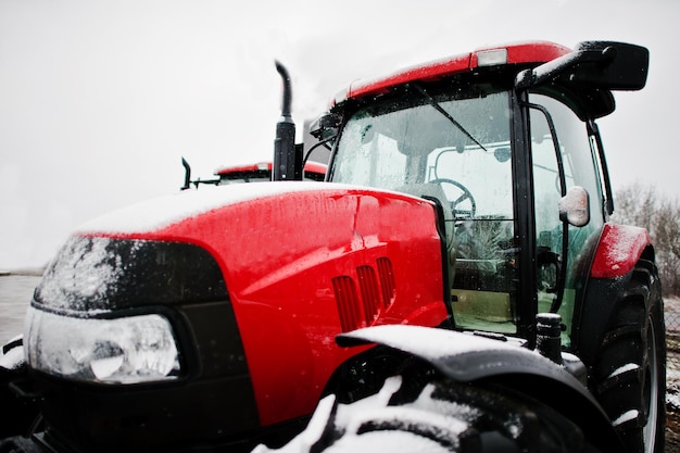 Cerrar en frente del nuevo tractor rojo en tiempo de nieve