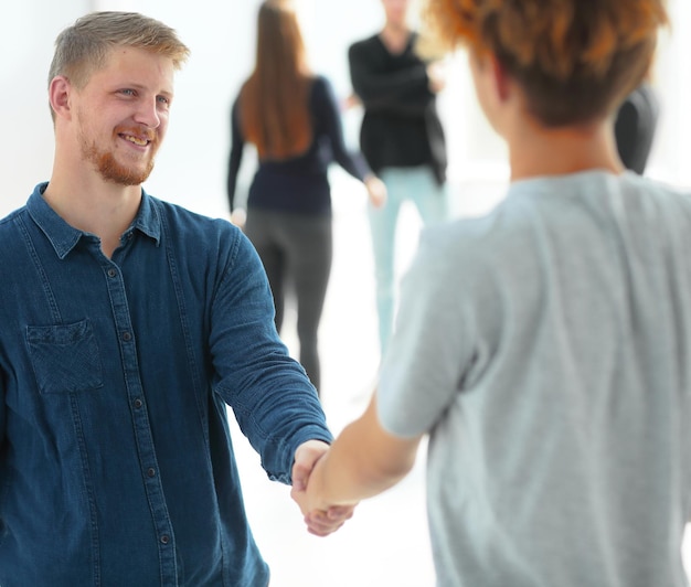 Cerrar Gerente estrechando la mano con un joven empleado