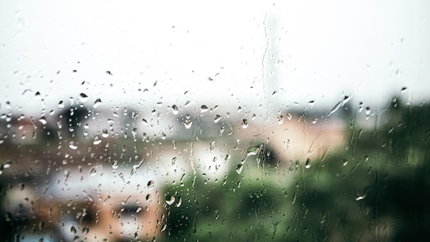 Cerrar gotas de agua de lluvia que caen burbujas sobre el vidrio de la ventana mojada