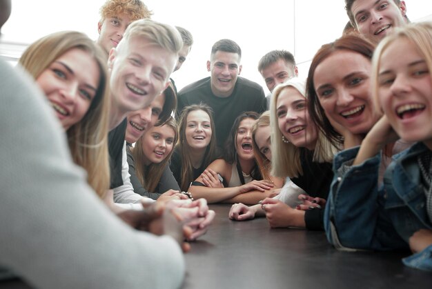 Cerrar un gran grupo de amigos sentados en una mesa larga