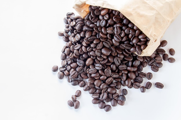 Cerrar granos de café en bolsa de papel sobre fondo blanco.