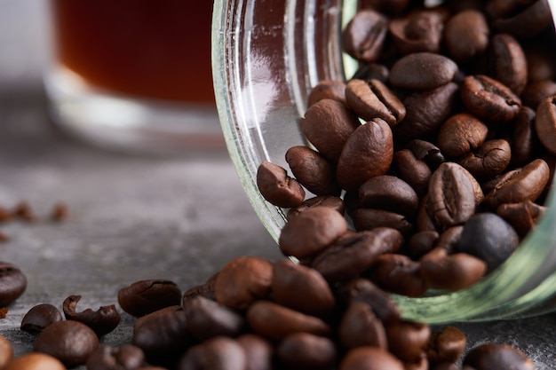 Cerrar los granos de café en un frasco de vidrio sobre la mesa de piedra gris