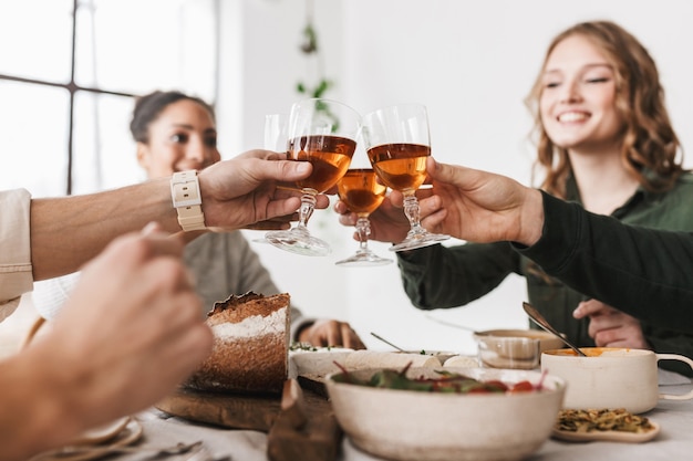 Cerrar grupo de amigos internacionales sentados a la mesa con copas de vino en las manos