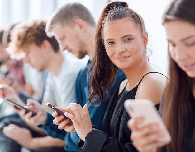 Cerrar un grupo de jóvenes serios mirando las pantallas de sus teléfonos inteligentes