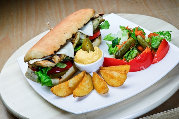 Cerrar una hamburguesa grande con filete de res con paneer, queso y verduras en el plato blanco en la mesa del restaurante servido