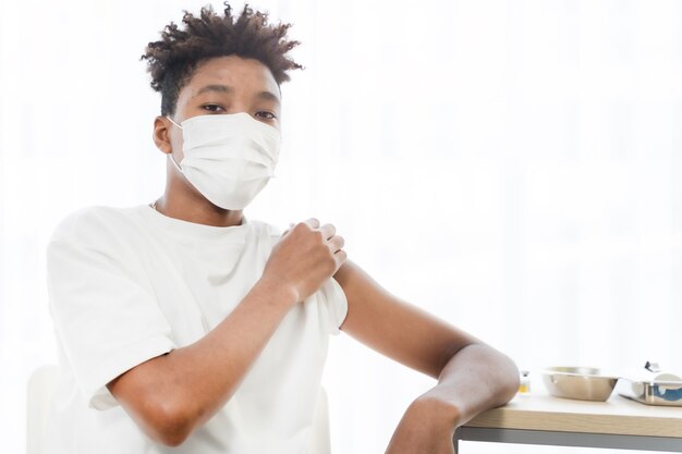 Cerrar hombre afroamericano preparando su hombro mientras recibe la vacuna covid en la clínica