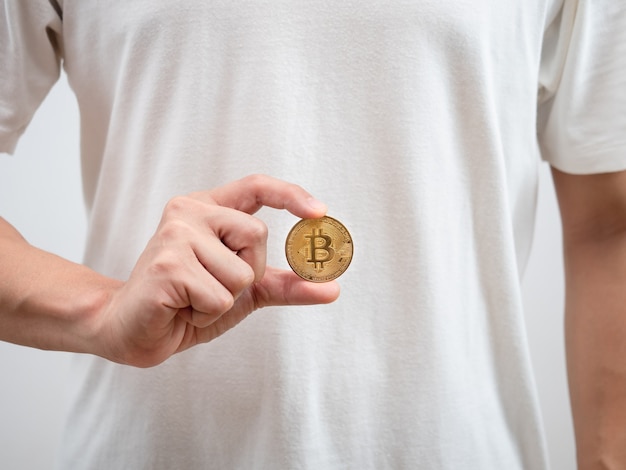 Cerrar hombre camisa blanca mostrar bitcoin dorado en su mano