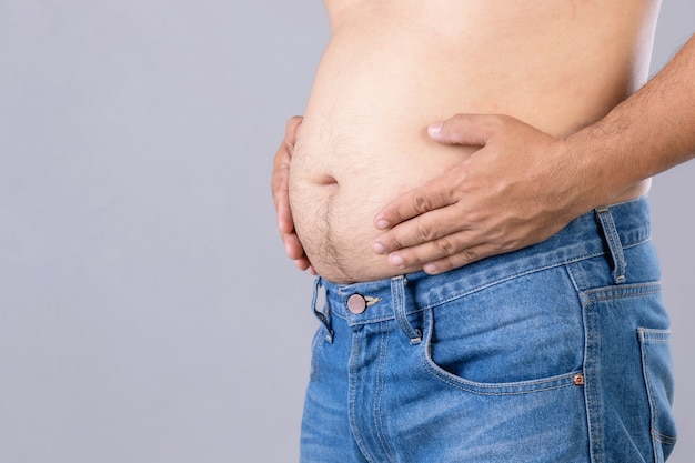 Cerrar hombre gordo de pie y mostrar su barriga con. Gente gorda y concepto saludable