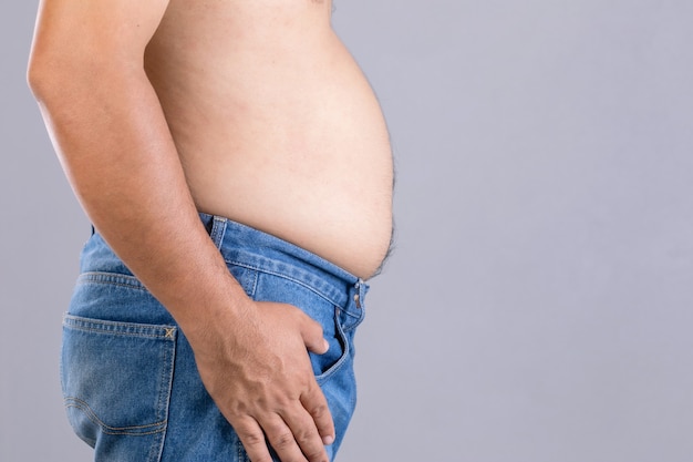 Cerrar hombre gordo de pie y mostrar su barriga con. Gente gorda y concepto saludable