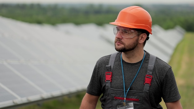 Cerrar hombre técnico de energía caminar sobre el campo de paneles solares e inspeccionar paneles solares fotovoltaicos. Concepto energía renovable, tecnología, verde, futuro.