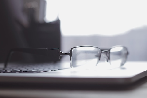 Cerrar imagen borrosa de gafas de hombre de negocios en el teclado de la computadora portátil