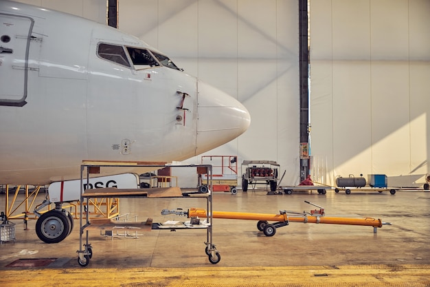 Cerrar imagen de la gran cabina blanca del avión de pasajeros de pie en la modernización programada en el aeródromo