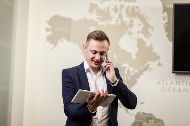 Cerrar imagen de hombre de negocios con una tableta digital, Retrato de hombre joven y guapo que trabaja con tableta en la oficina. Empresario inteligente y confiado con touch pad con infografía