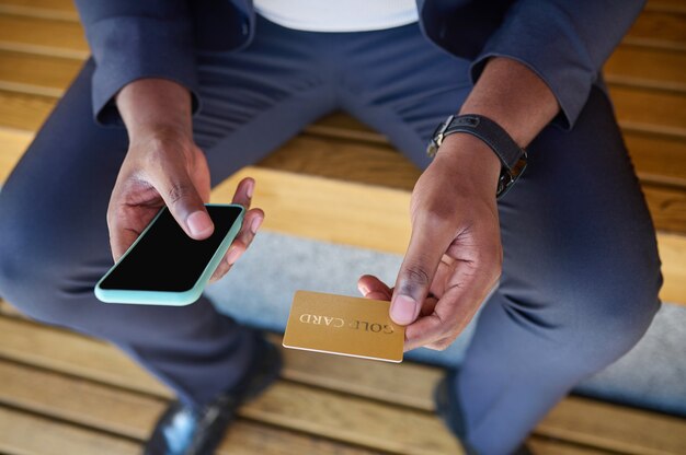 Cerrar imagen de un hombre con una tarjeta de crédito y un teléfono inteligente