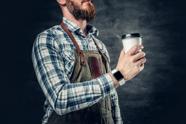 Cerrar imagen de macho barbudo pelirrojo sostiene una taza de café sobre fondo gris.